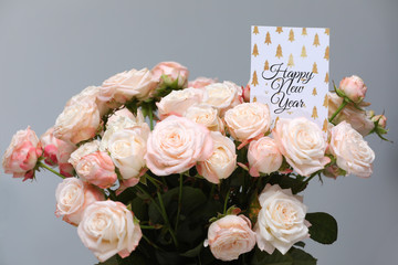 Close up beautiful Fresh pink roses flowers with Happy New Year greeting card on grey background. copy space.