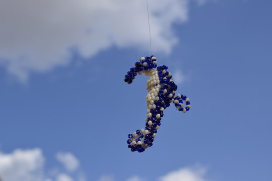Cavalo-marinho de miçanga pendurado contra céu azul