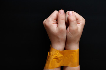 hands of a child tied with yellow tape. Violation of human rights, kidnapping.