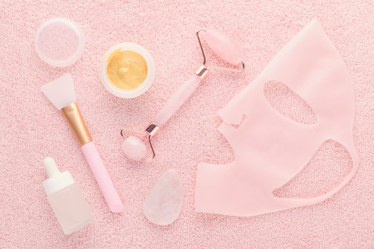 Golden Facial Cream Mask With A Brush, Jade Roller, Face Serum And Silicone Beauty Mask On Pink Background