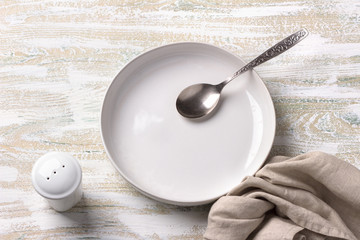 White plate with linen napkin on white wooden background	