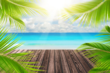 Fototapeta na wymiar Blur tropical beach with bokeh sun light wave and palm tree on empty old wood table abstract background.