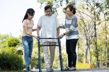 Asian senior woman use walking aid during rehabilitation after physical therapy or knee surgery,...