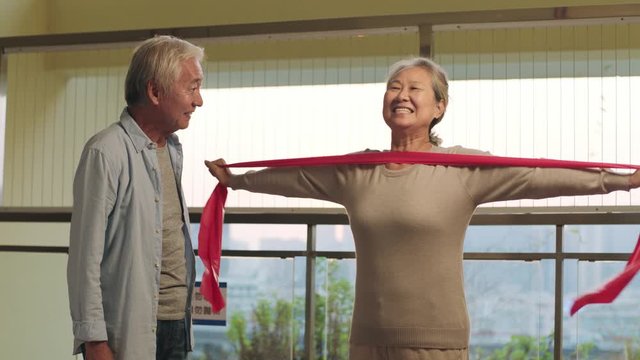 happy senior asian couple exercising using resistance band