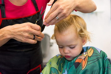 Cute blonde girl having her first haircut.