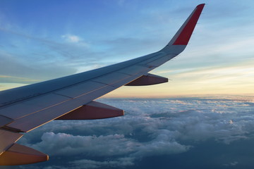 Obraz premium plane wing and cloud floating on sky through window frame on sunset