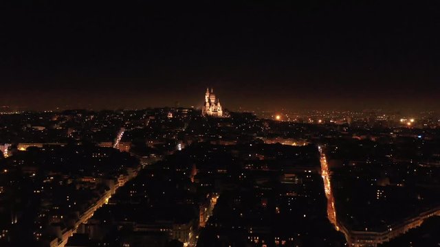 Basilica of the Sacred Heart of Paris by night aerial view Rochechouart neighbourhood roofs city lights Montmartre