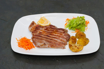 Juicy grilled meat steak with lemon, carrots, lettuce and potatoes.