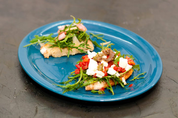 Bruschetta with shrimp, arugula, tomatoes, cheese and sauce. High Italian cuisine