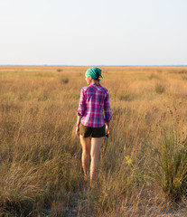 red-haired girl in spend time with pleasure in summer prairie at sunset