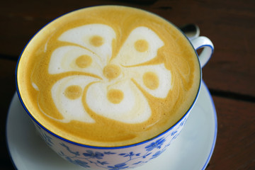 Cup of warm cappuccino coffee with a flower foam design on top