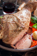 Baked turkey drumstick in a bowl, with a cut piece on a wooden table, selective focus