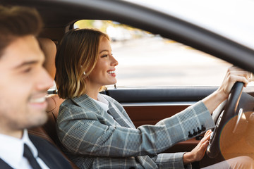 Image of young caucasian businesslike man and woman riding in car