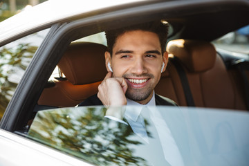 Image of young caucasian businesslike man in suit riding in car