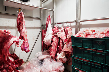 Lamb and veal carcasses hanging on hooks in the cold storege room of a slaughterhouse