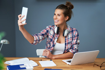 Female student learning at home and taking selfie