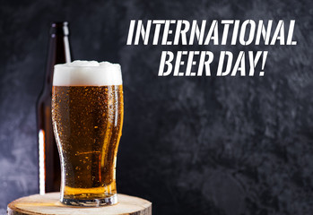 International beer day. Glass of light beer on a dark background