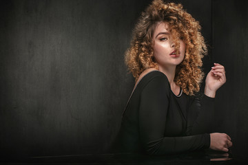 Elegant woman with curly hair posing.