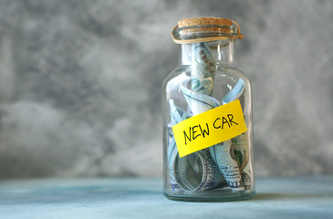 Money for new car concept with glass jar labeled new car filled with money.