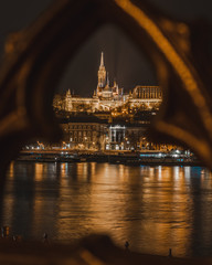 Fototapeta na wymiar Fisherman's bastion and Matthias Church of Budapest, Hungary through a balustrade with the Danube in front