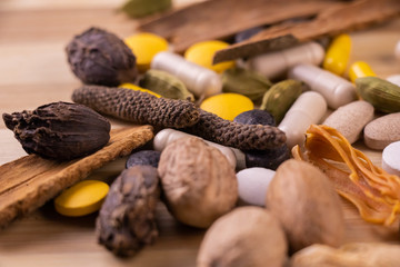 Top view macro shot of herbal pills and tablets arranged with spices on a red stone. Unani...