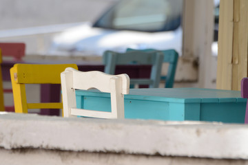 Outdoor colourful wooden chairs and tables behind stone wall