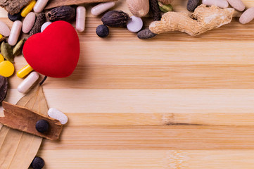 Top view macro shot of herbal pills and tablets arranged with spices on a red stone. Unani medicines concept.
