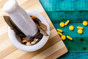 Top view macro shot of herbal pills and tablets arranged with spices on a red stone. Unani medicines concept.