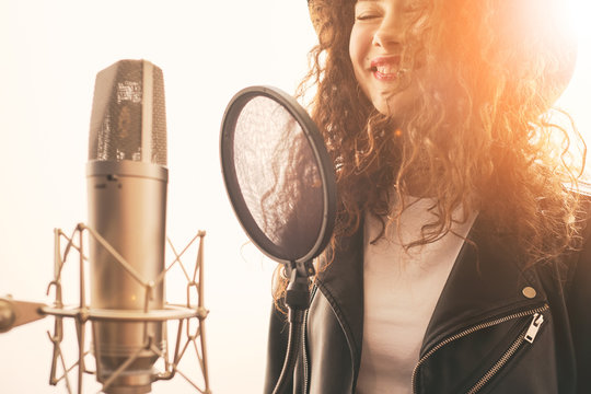 Happy female singer recording vocals