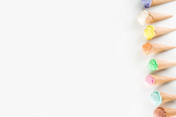 Colorful pastel ice cream with waffle cones, white background, copy space top view
