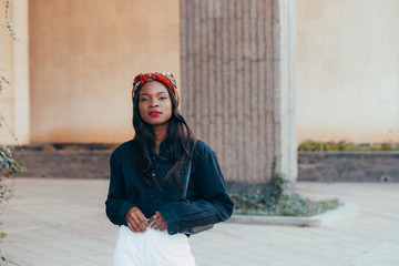 Beautiful young black african muslim girl wearing a bandana on the street of modern city. She is...
