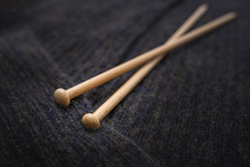 Nahaufnahme von hölzernen Stricknadeln für Handarbeit, liegen auf gemütlicher, flauschiger handgemachter gestrickter großer Decke, super weiche Merinowolle, zu Hause als Hintergrund