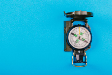 metal navigation travel compass on a blue background. search for a way. point of view