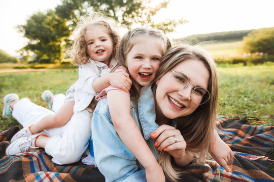 Blonde mother with two cute daughters are walking and having fun outdoors. Stylish, casual clothes.