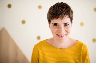 Front view of young woman standing indoors at home, close-up.