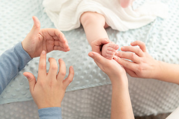 Female massage therapist teaching young mother how to massage her newborn baby boy. Baby massage concept. Cropped shot close up on hands.