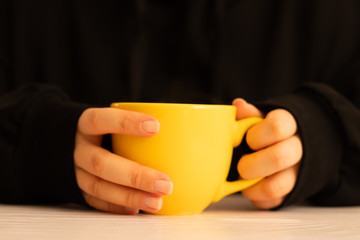 A cup of tea in the hands of young woman