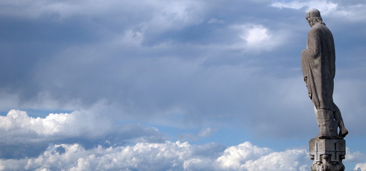 Sculpture of the saint against the blue cloudy sky on the roof of the cathedral in Milan.