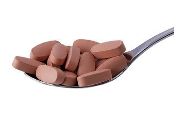 Vitamin pills on tablespoon isolated on white. Macro photography, food supplements. Concept for diet, health and nutrition.