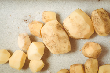 Peeled potatoes lie in kitchen sink for washing.