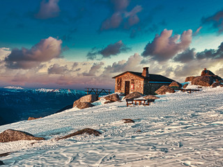 Casa en montaña con nieve, atardecer
