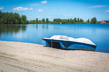 Large catamaran with pedals for riding on the water on the shore of blue lake.