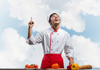 Young male chef standing near cooking table
