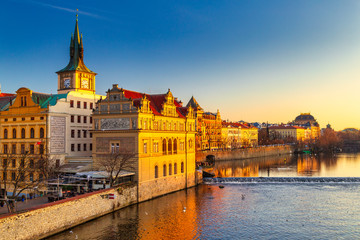 Historic buildings on the Vltava river bank at sunset in Prague, Czech Republic, Europe.