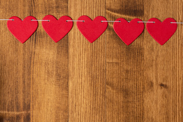 Bright red hearts hang on a rope on a wooden background, flat lay, top view, copy space. Background with red hearts for Valentine's day, wedding, holiday. Love and romance background.