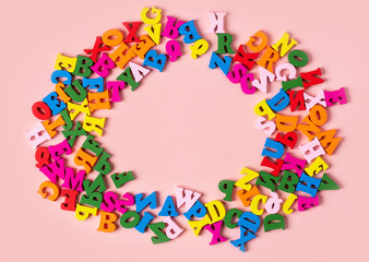 Multicolored wooden alphabet on a pink background, top view, flat lay, free space for text. Preschool or back to school concept.