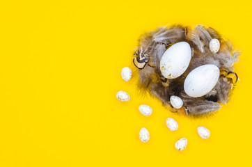 Trendy Easter flat lay with quail and chicken eggs in a nest. isolated on a yellow background. Copy space