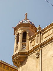 Balcony of an old stone building of sandy color with a blue tiled roof