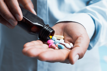 doctor pouring medicine out of bottle on hand. concept health care and medical