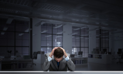 Frustrated man sitting at desk with hands on head